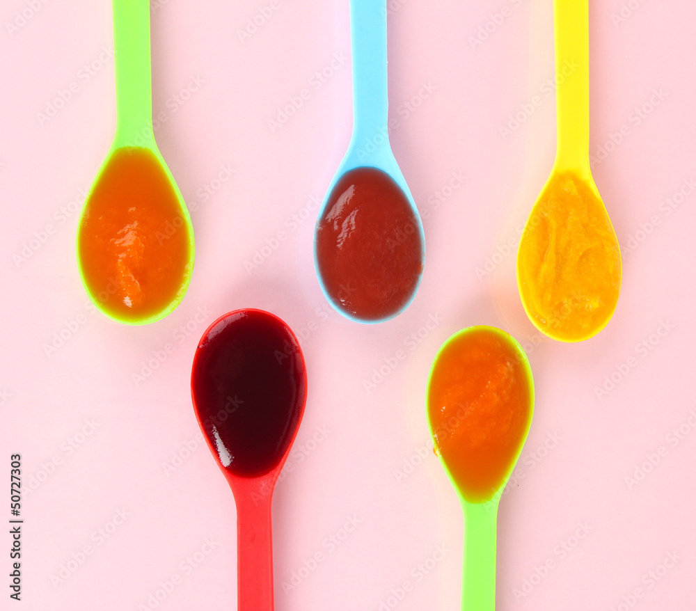 Baby puree in spoons on pink background