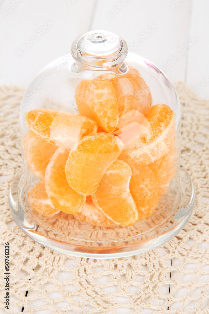 Tangerine on saucer under glass cover on light background