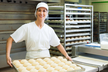 Female baker baking bread rolls