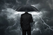 Businessman With Umbrella Standing In Front Of Storm