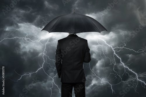 Fotografie, Obraz Businessman with umbrella standing in front of storm