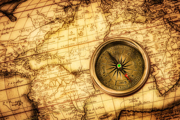 vintage compass lies on an ancient world map.