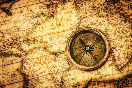 Fototapeta na wymiar Vintage compass lies on an ancient world map.