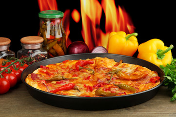 Wall Mural - Tasty pepperoni pizza in pan with vegetables on flame