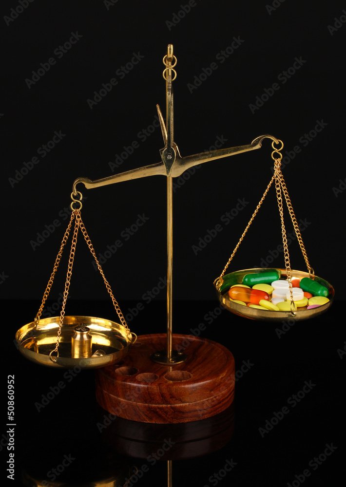 Classic scales with color pills isolated on black