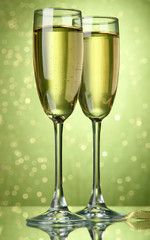 Two glasses of champagne on bright background with lights