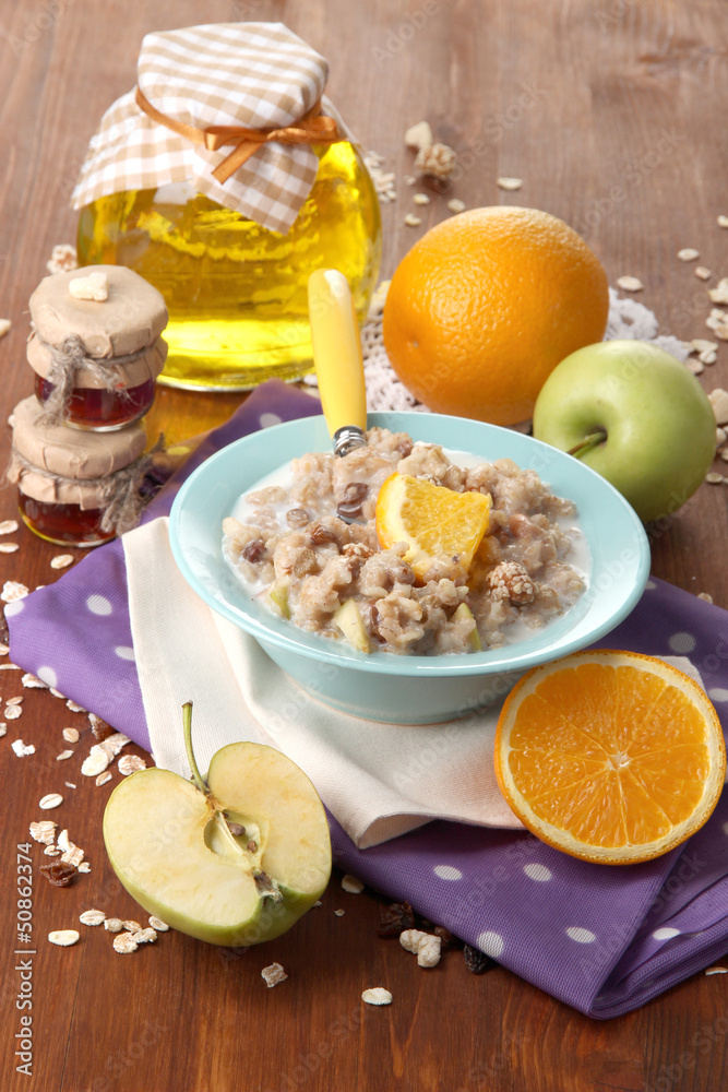 Useful oatmeal in bowl with fruit on wooden table close-up