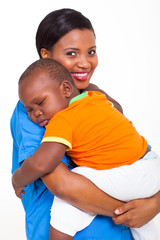 Wall Mural - portrait of young african nurse carrying sleeping baby boy