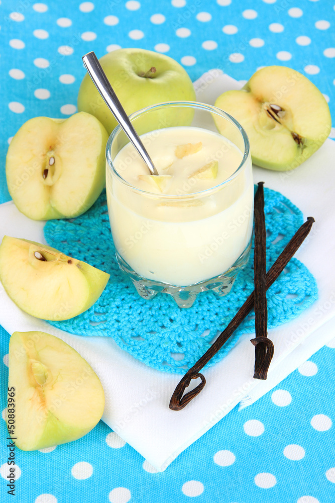 Delicious yogurt in glass with apple on blue tablecloth