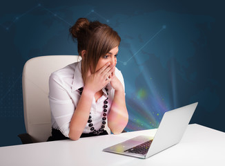 Beautiful woman sitting at desk and typing on laptop with abstra