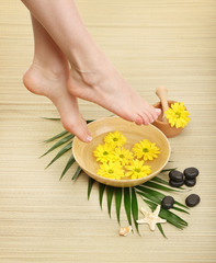 Wall Mural - Female feet in spa bowl with water, on bamboo mat