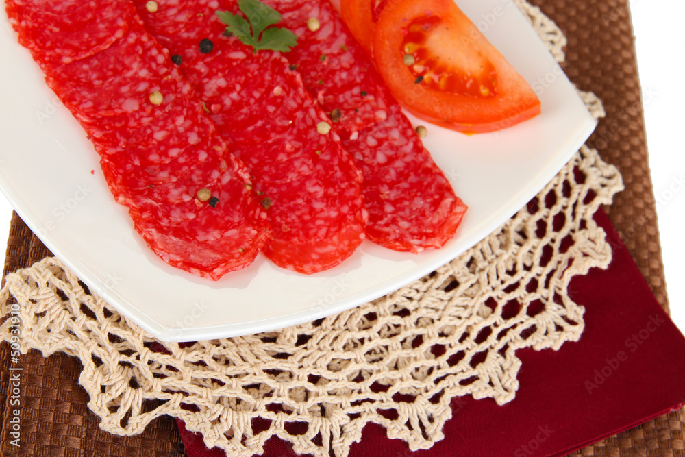Tasty salami on plate on  napkin isolated on white