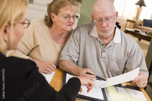 Fotografie, Obraz Senior Adult Couple Going Over Papers in Their Home with Agent