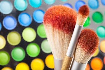 makeup brushes and set of colorful eye shadows as background