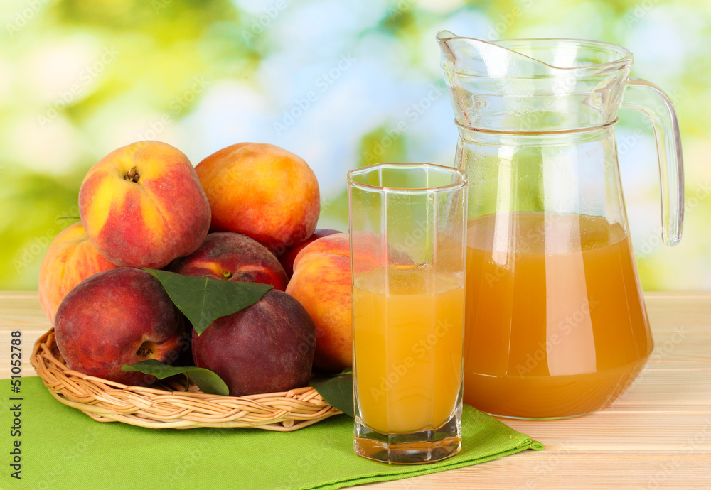 Ripe peaches and juice on wooden table on natural background