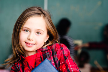 happy little schoolgirl portrait in classroom