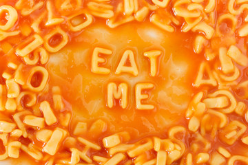 Pasta shaped letters spelling EAT ME in tomato sauce