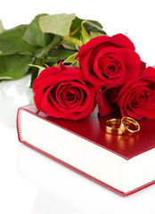 Wall Mural - Wedding rings with roses on bible isolated on white