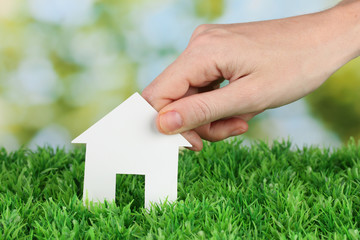 Sticker - Female hand holding paper house on green background, close up