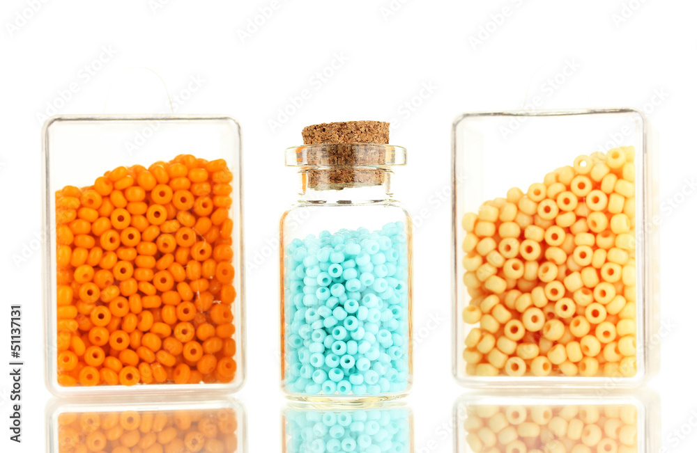 Colorful beads heap in boxes and glass bottle isolated on white