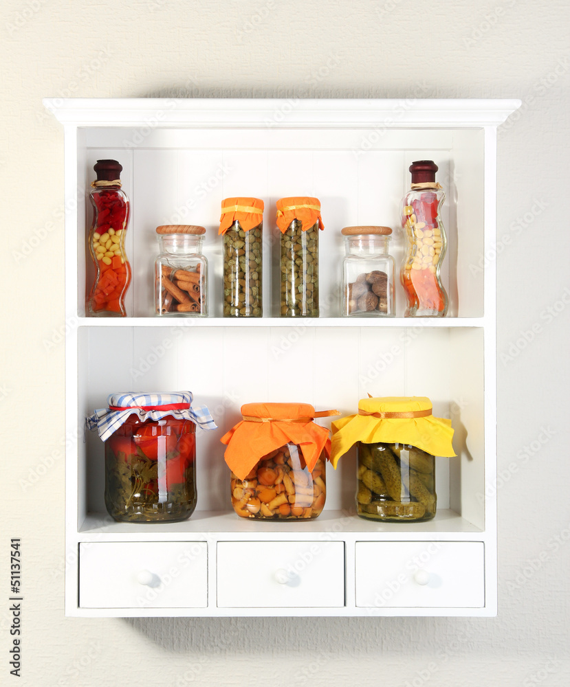 Homemade preserves and some spices on beautiful white shelves