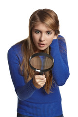 astonished girl looking through the magnifying glass downwards