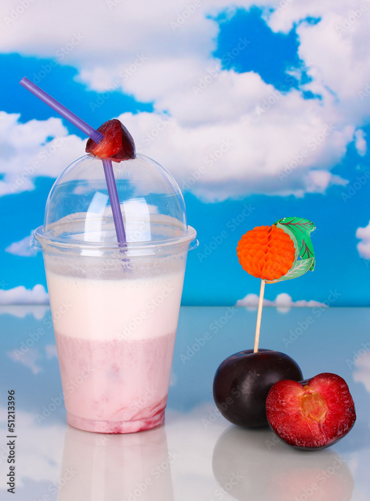 Delicious milk shake with fruit on table on blue sea background