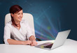 © ra2 studio - Beautiful woman sitting at desk and typing on laptop with abstra