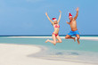 © Monkey Business - Couple Jumping On Beach Wearing Santa Hats