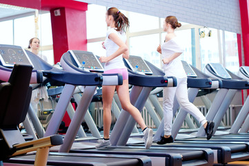 Two young sporty women run on machine