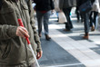 Blind person with white cane in public place