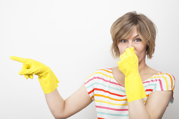 Young beautiful woman in rubber gloves holding her nose