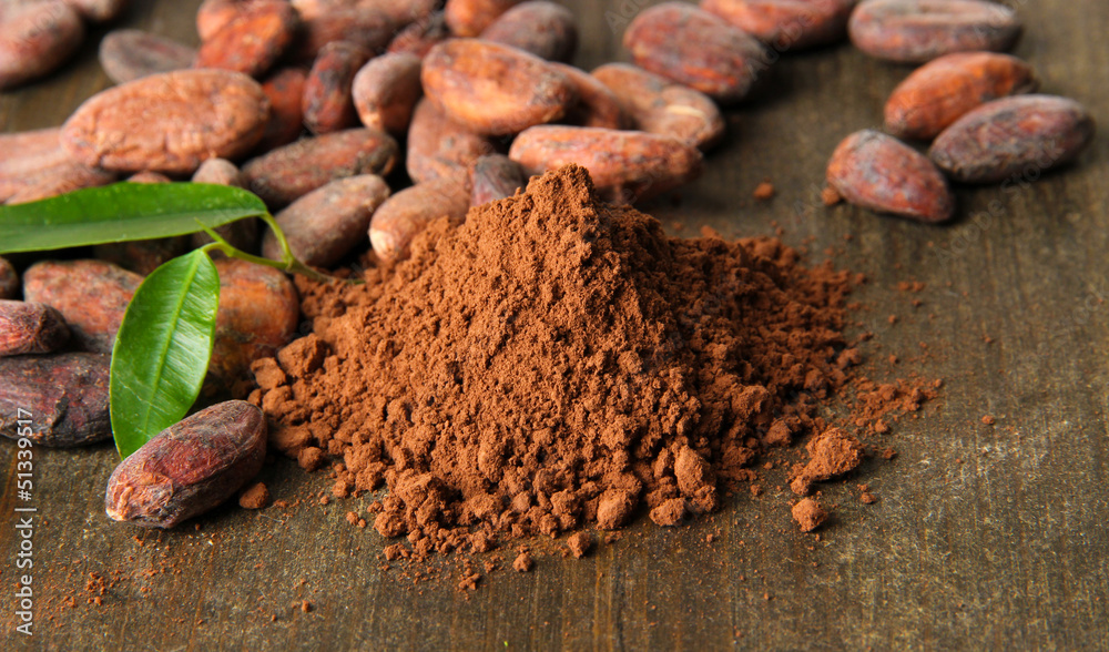 Cocoa beans and cocoa powder on wooden background
