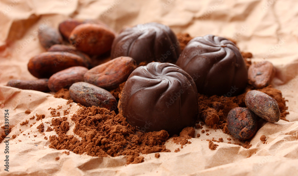 Composition of chocolate sweets and cocoa on brown background