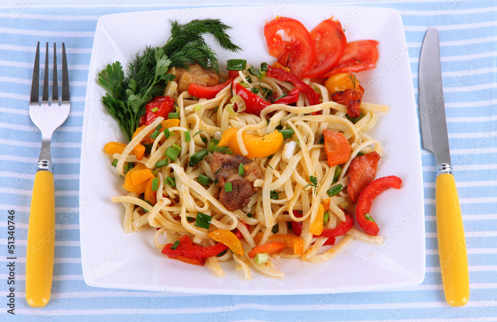 Noodles with vegetables on plate on napkin isolated on white