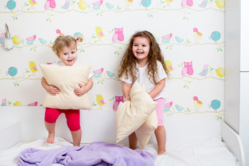 children sisters playing on the bed indoors