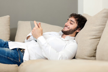 Wall Mural - Portrait of young man relaxing in sofa with electronic tablet