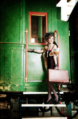 Retro girl with suitcase near the old train