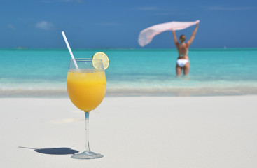 Wall Mural - Glass of orange juice on the sandy beach of Exuma, Bahamas