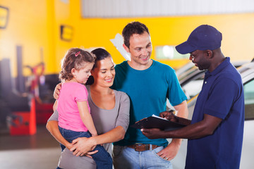 Wall Mural - friendly auto mechanic talking to young family