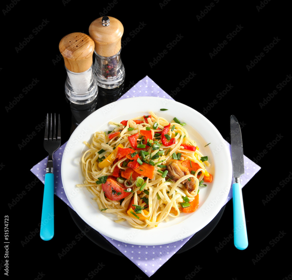Noodles with vegetables on plate isolated on black