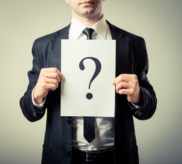 businessman holding a white billboard with a question mark on it