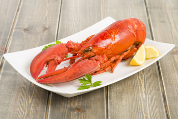 Lobster and lemon wedges on a wooden table.