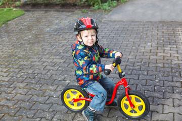 Wall Mural - 2 years old toddler riding on his first bike