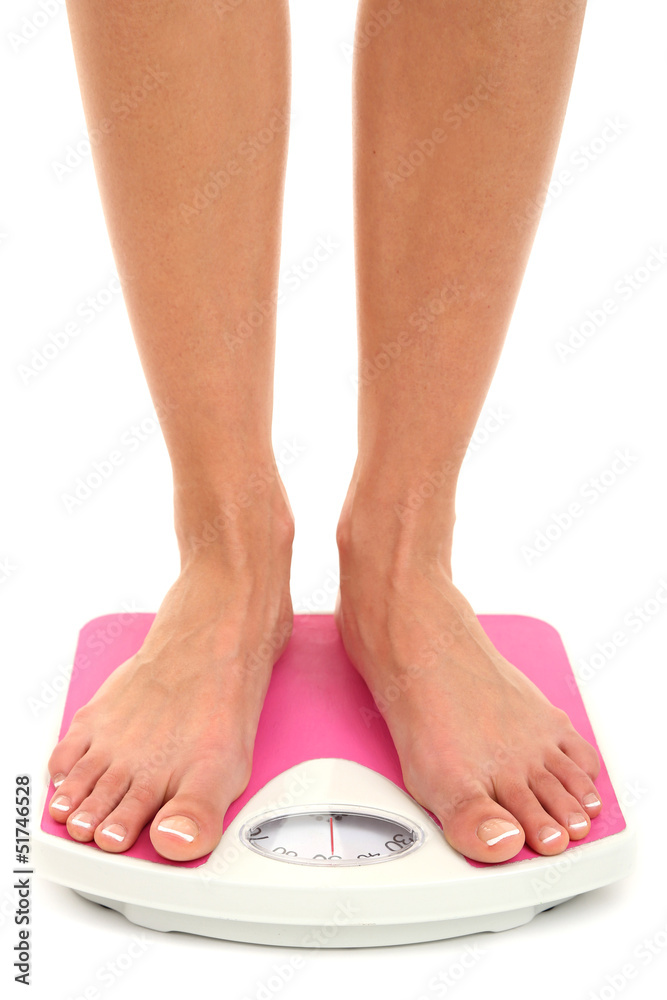 Bare female feet standing on scale isolated on white