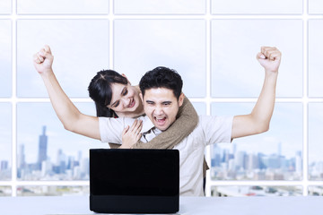 Happy couple with laptop in office