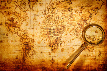 vintage magnifying glass lies on an ancient world map