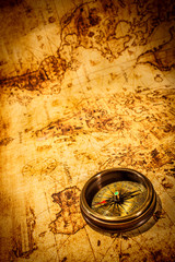 vintage compass lies on an ancient world map.