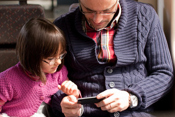 father and daughter on train with smart phone