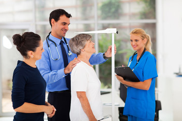 general practitioner measuring senior patient's height